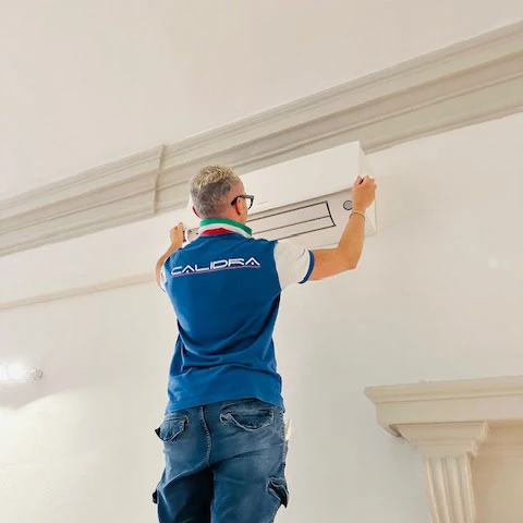 Installazione di un condizionatore in abitazione privata Installazione condizionatori a Bologna: tecnico di Calidra mentre posiziona un climatizzatore in una abitazione